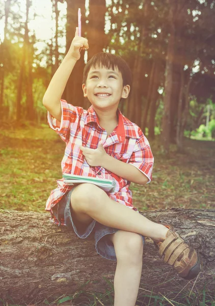 Gelukkig Aziatische kind lachend op houten log in nationaal park. Planning kinderen en onderwijs concept. — Stockfoto