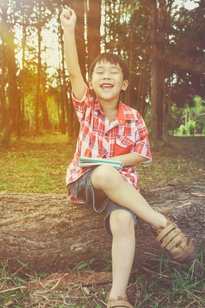 Gelukkig Aziatische kind lachend op houten log in nationaal park. Buiten — Stockfoto