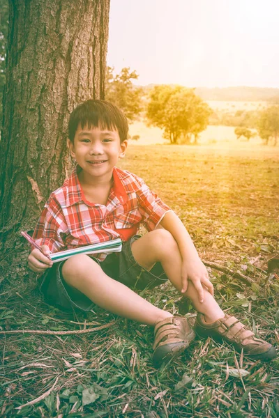 Szczęśliwy chłopiec azjatyckich, uśmiechając się i trzyma książkę. Koncepcja edukacji. Dźwięk w Vintage. — Zdjęcie stockowe