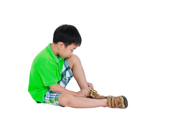 Vista lateral de niño asiático poner zapatos de cuero. Aislado sobre fondo blanco . — Foto de Stock