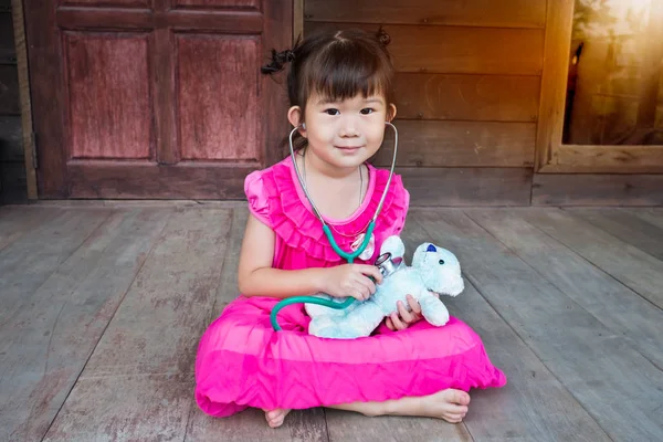 Очаровательная азиатка, играющая в доктора или медсестру с плюшевым игрушечным мишкой — стоковое фото