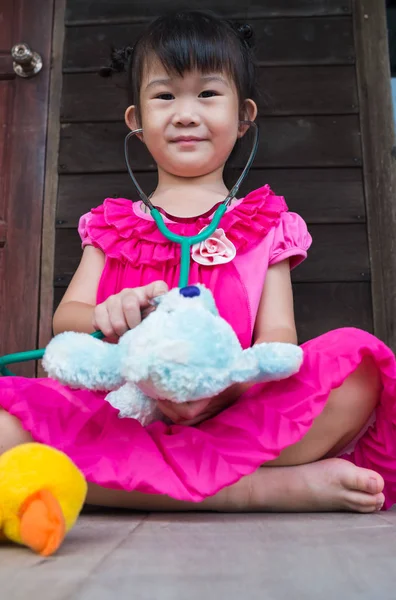 Adorable asian girl playing doctor or nurse with plush toy bear — Stock Photo, Image