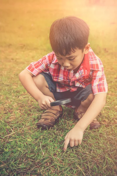 Niño explorando la naturaleza con lupa. Al aire libre durante el día. Concepto educativo . —  Fotos de Stock