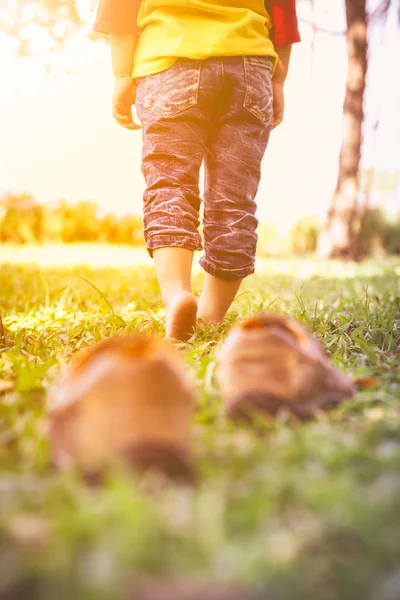 La chica se quita los zapatos. El pie del niño aprende a caminar sobre la hierba, masaje reflexológico . — Foto de Stock