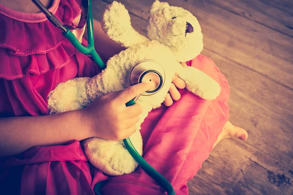 Criança brincando de médico ou enfermeira com urso de pelúcia em casa . — Fotografia de Stock