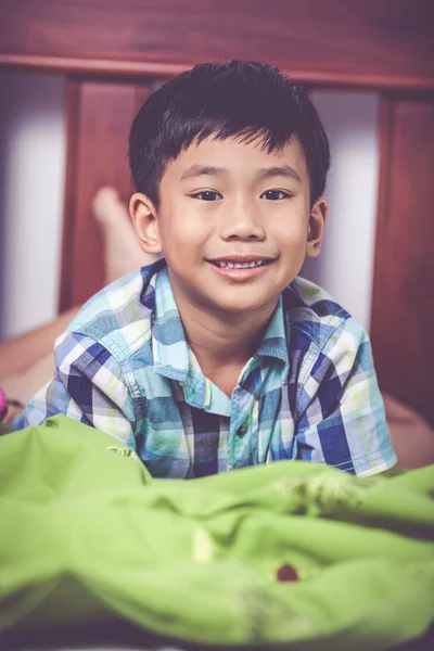 Schöner Junge, der barfuß auf dem Bett im Schlafzimmer liegt. glückliches Kind lächelt. — Stockfoto