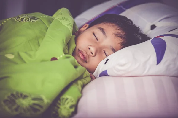 Gezond kind. Aziatische jongetje slapen rustig op bed. Vintage Toon effect. — Stockfoto