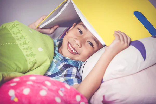 Z bliska. Chłopiec azjatyckich obejmujące głowę z książki i uśmiecha się. Koncepcja edukacji. — Zdjęcie stockowe