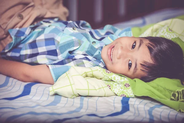 寝室のベッドの上に横たわるハンサムな男の子の肖像画。ビンテージ トーン. — ストック写真