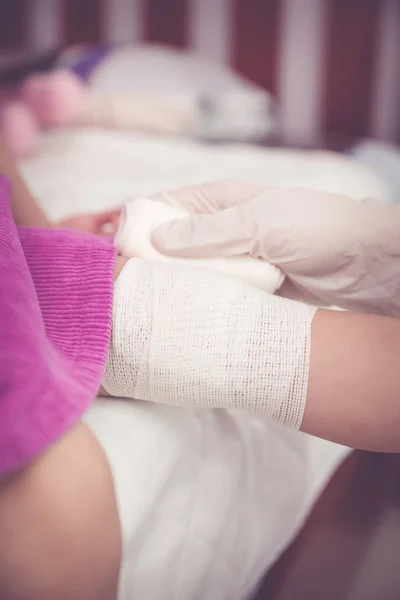 Bambino ferito. Medico pediatra che bendava il ginocchio del bambino. Effetto tono vintage — Foto Stock