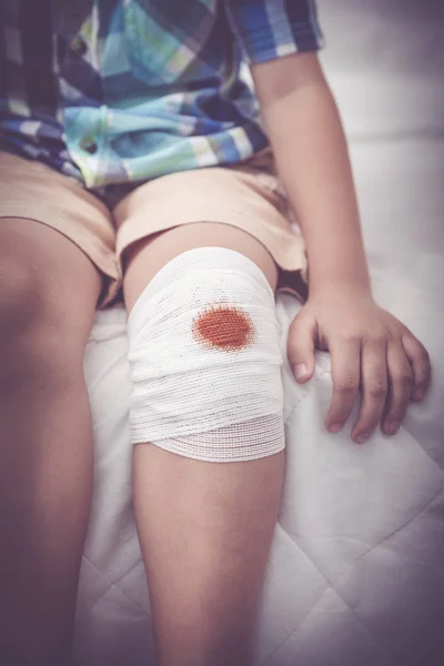 Ребенок ранен Ранение на колене ребенка бинтом. Эффект винтажного тона . — стоковое фото