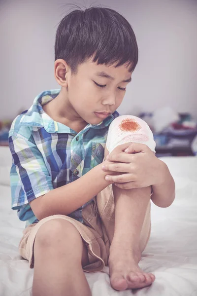 Enfant blessé. Blessure au genou de l'enfant avec bandage. Effet ton vintage . — Photo