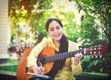 Güzel söz yazarı tarafından akustik gitar ile bir not kağıdına yazmak.