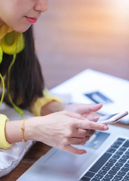 Kvinnans händer använder mobiltelefon och bärbar dator på våningen trä. — Stockfoto