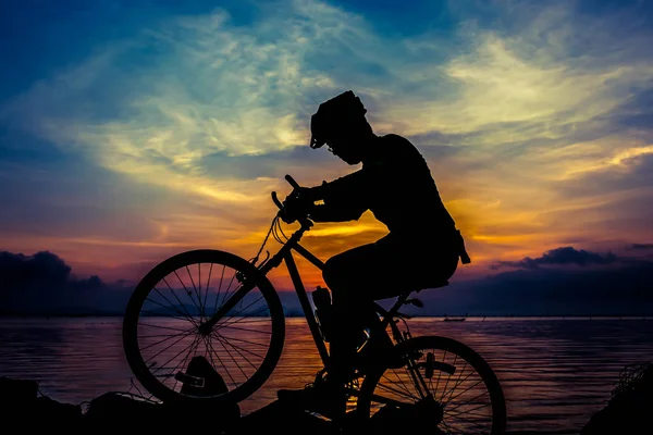 Uno stile di vita sano. Silhouette del ciclista in sella alla bici al mare — Foto Stock