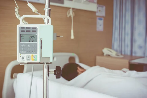 Asyalı çocuk hasta yatağının üzerinde infüzyon pompa intravenöz IV DRI ile yalan — Stok fotoğraf