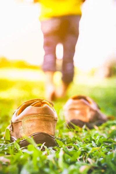 La chica se quita los zapatos. El pie del niño aprende a caminar sobre la hierba . — Foto de Stock