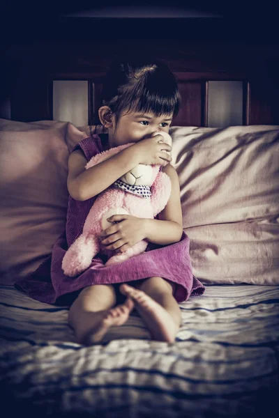 Sad asian girl sitting on bed. Vignette picture style. Low key and high contrast effect. — Stock Photo, Image