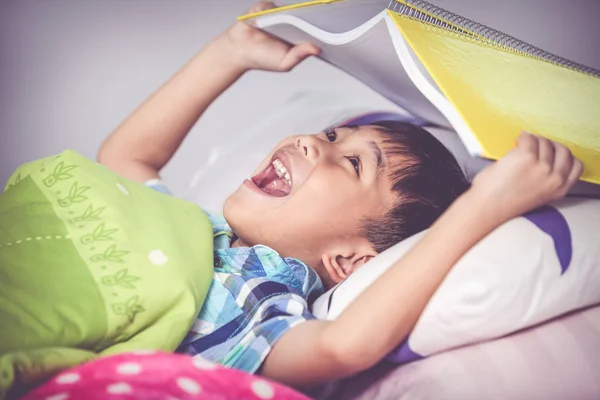 Menino asiático surpreso, criança cobrindo a cabeça com livro. Tom vintage — Fotografia de Stock