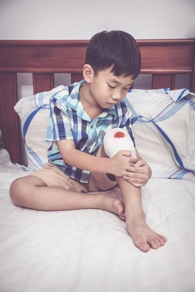 Niño herido. Herida en la rodilla del niño con vendaje. Tono vintage . — Foto de Stock