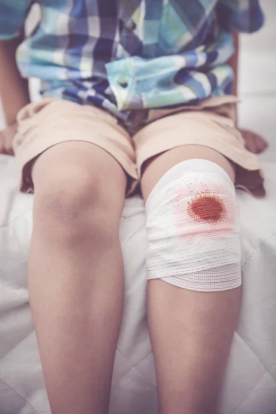Enfant blessé. Blessure au genou de l'enfant avec bandage. Ton effet vintage . — Photo