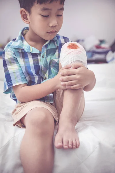 Bambino ferito. Ferito sul ginocchio del bambino con una benda. tono vintage . — Foto Stock
