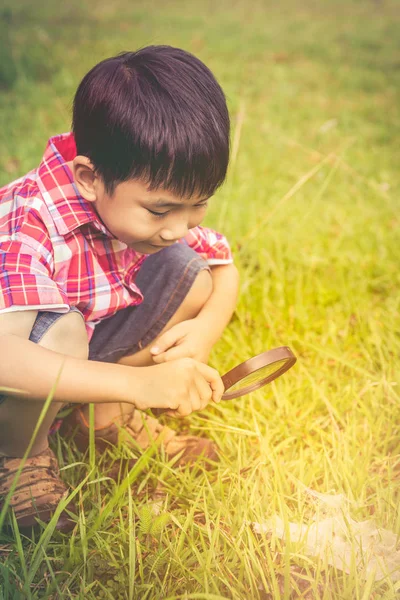 Jeune garçon explorant la nature avec une loupe. En plein air le jour d'été . — Photo