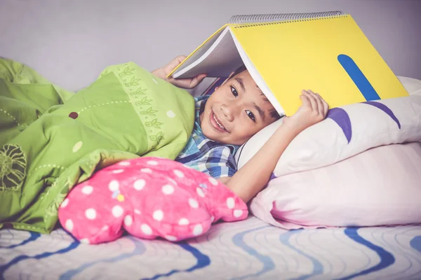 Fecha. Menino asiático cobrindo a cabeça com livro e sorrindo. Conceitos de educação . — Fotografia de Stock
