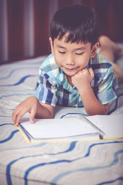 Un chico asiático leyendo un libro. Concepto educativo. Efecto tono Vintage — Foto de Stock
