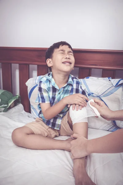 Kind verletzt. Mutter bandagiert Sohn das Knie. Vintage-Ton. — Stockfoto