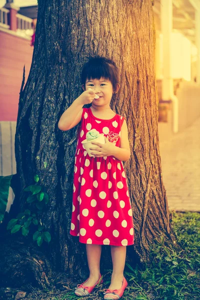 Rozkošná Asijská dívka jíst zmrzlinu v letním dni. Venku na letní den. — Stock fotografie