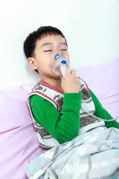 Niño asiático cerrando los ojos y sostiene una máscara inhalador de vapor para trea —  Fotos de Stock