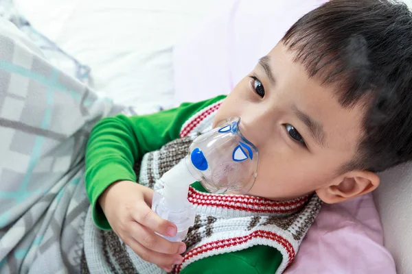 Bovenaanzicht van Aziatische kind houdt een masker damp inhalator voor de behandeling van astma — Stockfoto