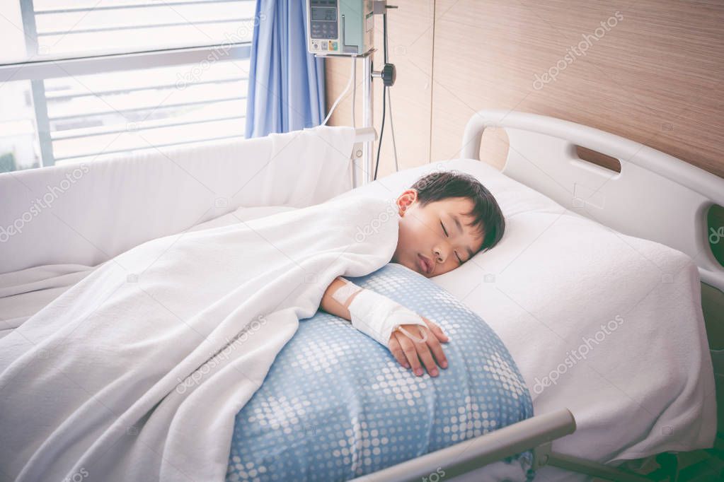 Asian boy lying on sickbed with saline intravenous (IV). Health care and people concept. 