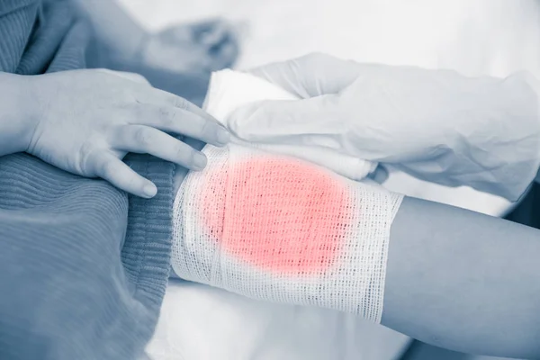 Child injured. Doctor bandaging child's knee. Human healthcare and medicine concept. — Stock Photo, Image