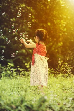 Asyalı kız sabun köpüğü doğa arka planda yakalar. Açık havada. 