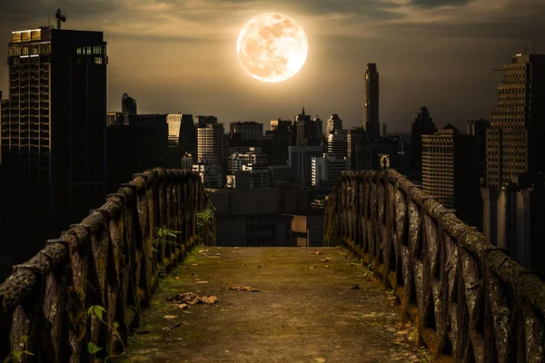 Oude betonnen brug over aan wolkenkrabbers met super maan achtergrond. — Stockfoto