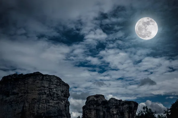 Rocas contra el cielo con nubes y hermosa luna llena cerca — Foto de Stock