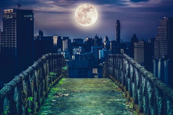 Viejo puente de hormigón a través de rascacielos con fondo super luna . — Foto de Stock