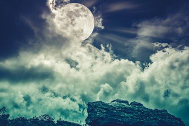 Boulder gökyüzü bulutlar ve güzel dolunay ile karşı. İşlem çapraz.