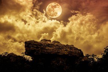 Bulutlar ve güzel Dolunay geceleri gökyüzüne karşı kayalar
