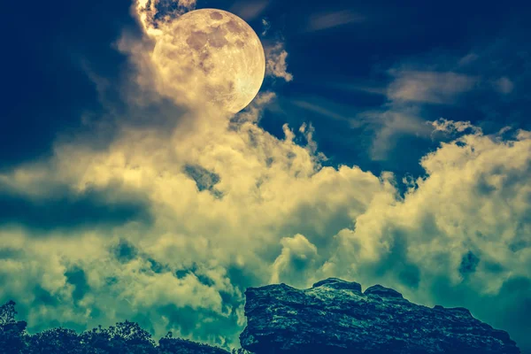 Boulder contra el cielo con nubes y hermosa luna llena. Proceso cruzado . — Foto de Stock