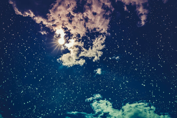 Amazing blue dark night sky with many stars, bright full moon and cloudy. Outdoor at nighttime with moonlight. Pretty nature use as background. Cross process and vintage effect tone.
