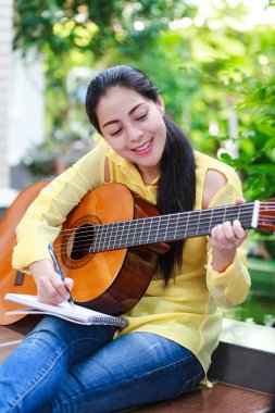 Güzel söz yazarı tarafından akustik gitar ile bir not kağıdına yazmak.