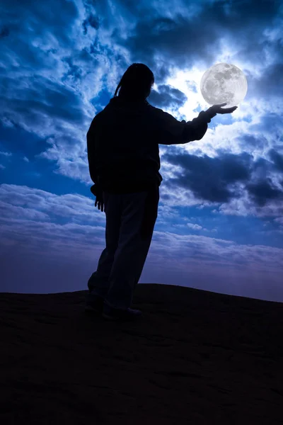 Силует задній вид жінки, що стоїть з повним місяцем тримається на долоні . — стокове фото