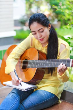 Akustik gitar ile bir not kağıdına yazmak güzel söz yazarı 
