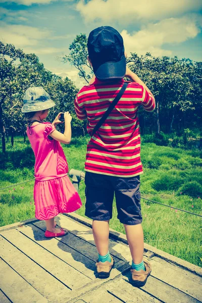 Vista trasera de niños asiáticos relajándose al aire libre durante el día, viajar de vacaciones . — Foto de Stock