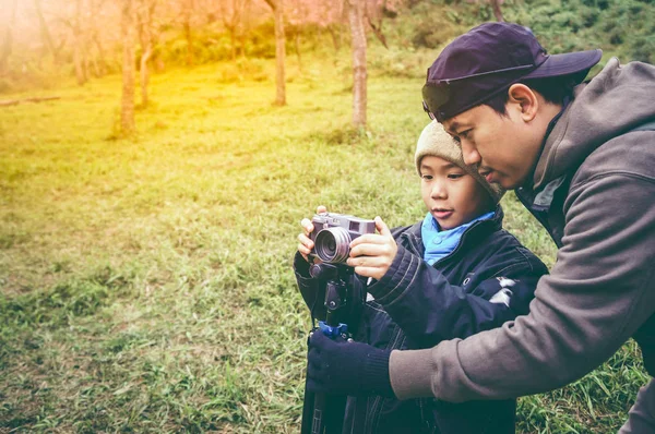Счастливая семья. Отец учит своего сына фотографировать на природе в лесу . — стоковое фото
