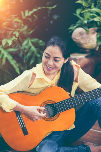 Asian kobieta gra gitara akustyczna z jasnym świetle słonecznym. Dźwięk w Vintage. — Zdjęcie stockowe