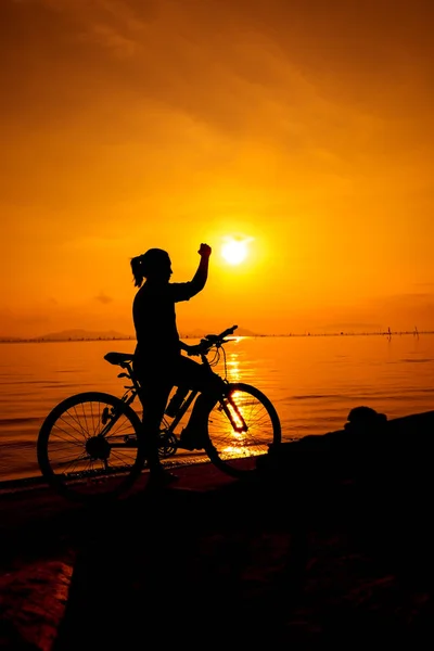 Silhouette einer Frau, die ihren Arm in Richtung Sonne reckt. Konzept der sensiblen Menschen. — Stockfoto